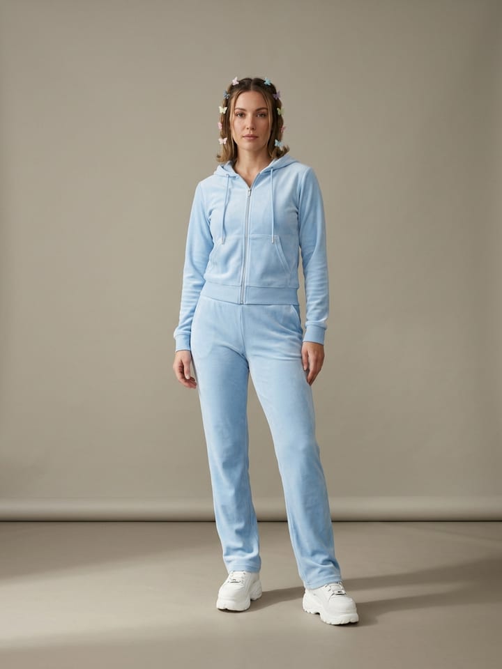 Woman in a baby blue velour zip hoodie and matching velour track pants, wearing chunky white sneakers and butterfly hair clips.